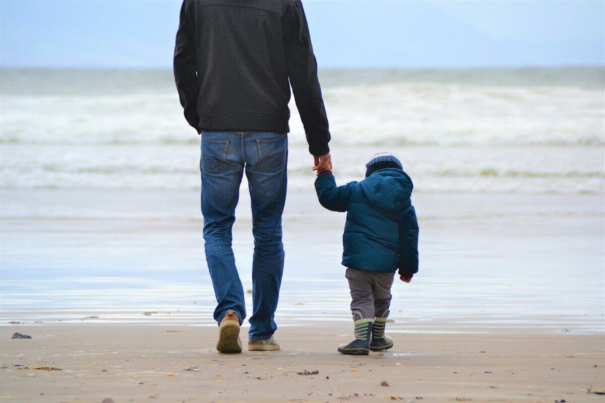 A paternidade de Deus: foto de um pai e seu filho caminhando na praia.